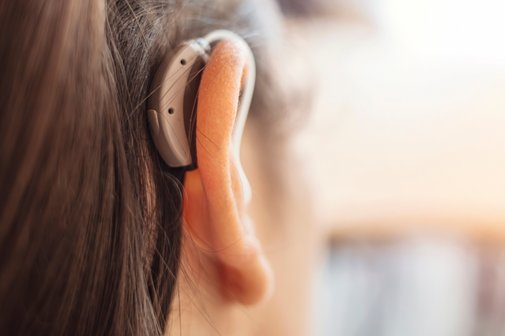 Kopf einer Frau mit einem Hörgerät hinter dem rechten Ohr.