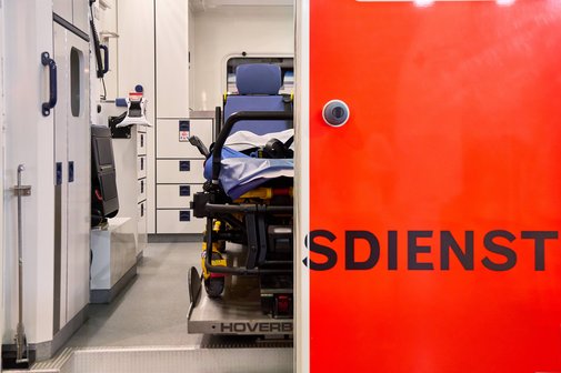 Blick in einen Rettungswagen, die linke Tür ist geöffnet und gewährt den Blick ins Innere, die rechte Tür ist geschlossen, so dass nur die Buchstaben "sdienst" des Wortes Rettungsdienst zu lesen sind.