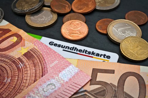 Gesundheitssystem Kosten Geldscheine und Münzen, darunter liegt eine Gesundheitskarte.