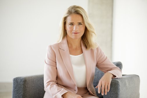 Das Foto zeigt Verena Bentele, sie sitzt in einem grauen Sessel und hat einen Arm auf der Lehne abgelegt