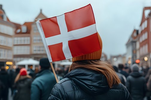 Eine Menschenmenge in einer Stadt, jemand tr&auml;gt eine d&auml;nische Flagge