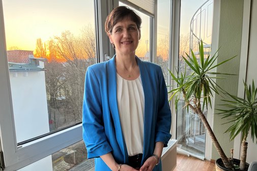 Katja Urbatsch am Fenster, neben ihr eine Zimmerpflanze