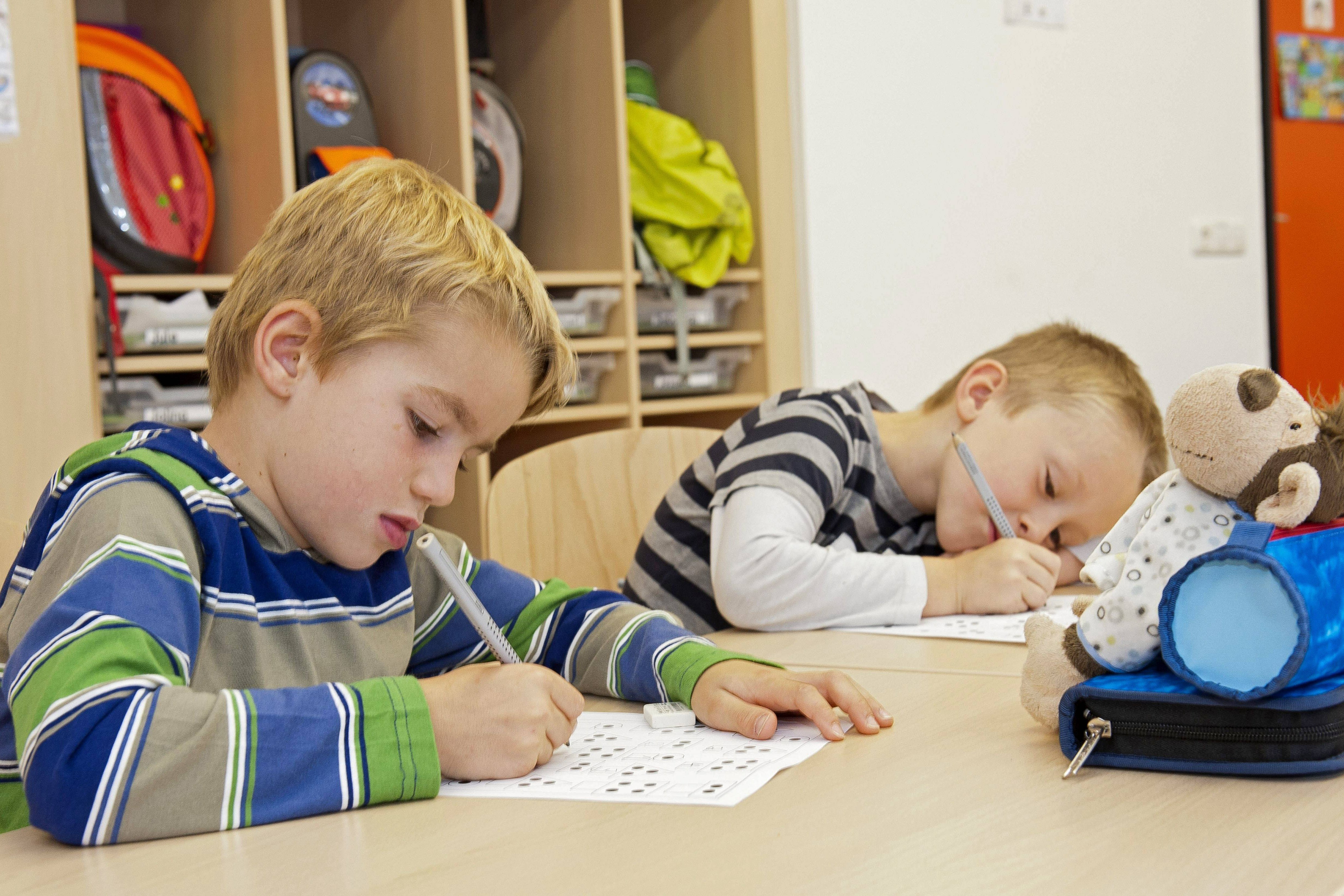 Kinder in einer inklusiven Schule Zwei Erstklässler sitzen in einer Schule am Tisch, schreiben etwas auf ein Arbeitsblatt.