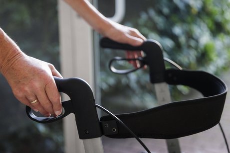 Gehen am Rollator Hände eines älteren Mannes halten die Griffe eines Rollators.