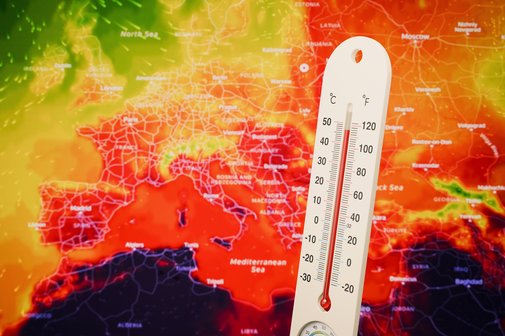 Die Bildmontage zeigt ein Thermometer, das eine extrem hohe Temperatur anzeigt vor einer Karte von Europa die überwiegend rot eingefärbt ist als Hinweis auf heißes Wetter.